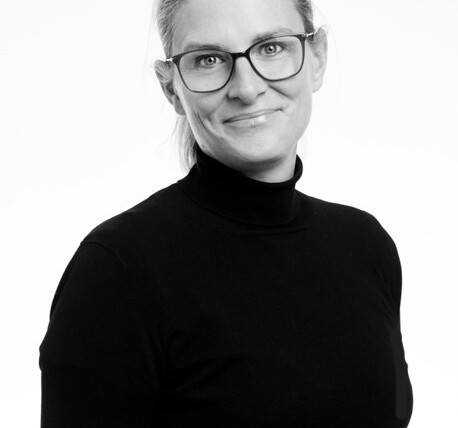 Porträtt av Annika Kurtsson, VD för Nynäshamnsbostäder, iförd glasögon och en mörk tröja med hög krage.