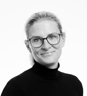 Porträtt av Annika Kurtsson, VD för Nynäshamnsbostäder, iförd glasögon och en mörk tröja med hög krage.